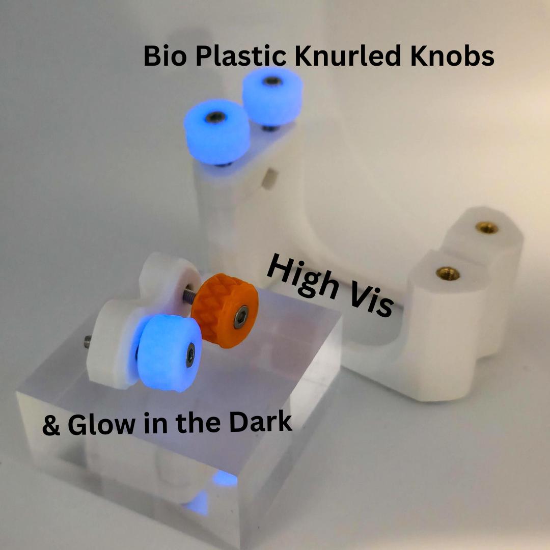 Glow-in-the-dark and high-visibility bioplastic knurled knobs installed on the Gem-Xfer jig. The blue fluorescent knobs are illuminated under UV light. Demonstrates optional materials users can print when building the digital STL version of the epoxy cure station, improving visibility during stone setting and alignment.
