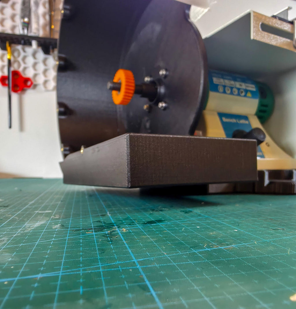 Front angled view of the lathe setup with the adapter plate visible beneath the machine, showing the clearance added from the adapter base. Reduce vibrations and increases stability.