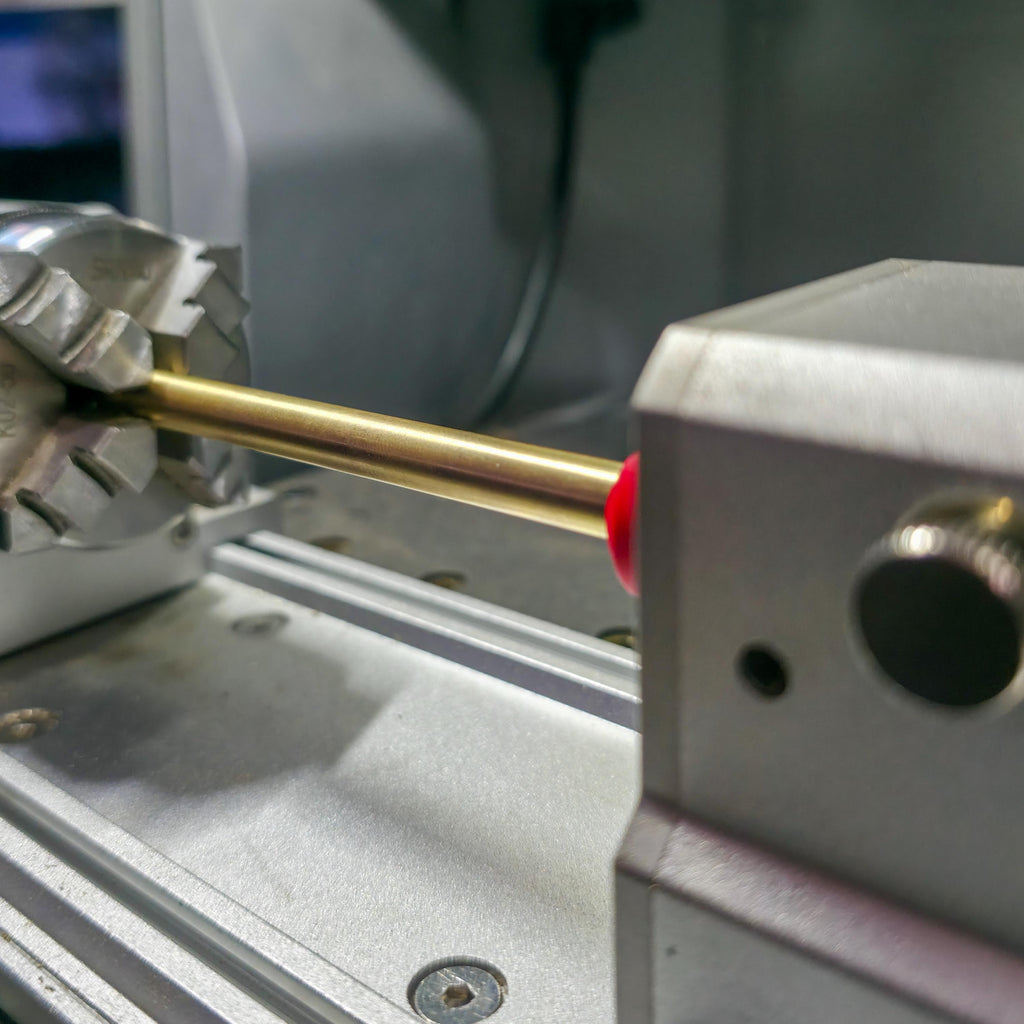 Rotary head assembly on a CNC baseplate fitted with a red alignment jig. Multiple guide pins and fixture bolts are visible, showing a typical maker setup for precision stock alignment.