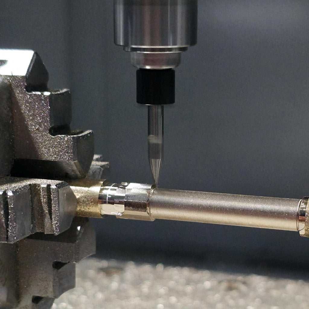 Close-up macro of CNC spindle tool engraving a brass rod held between two rotary chucks. Metal shavings reflect under bright workshop lighting, showing high-precision machining.