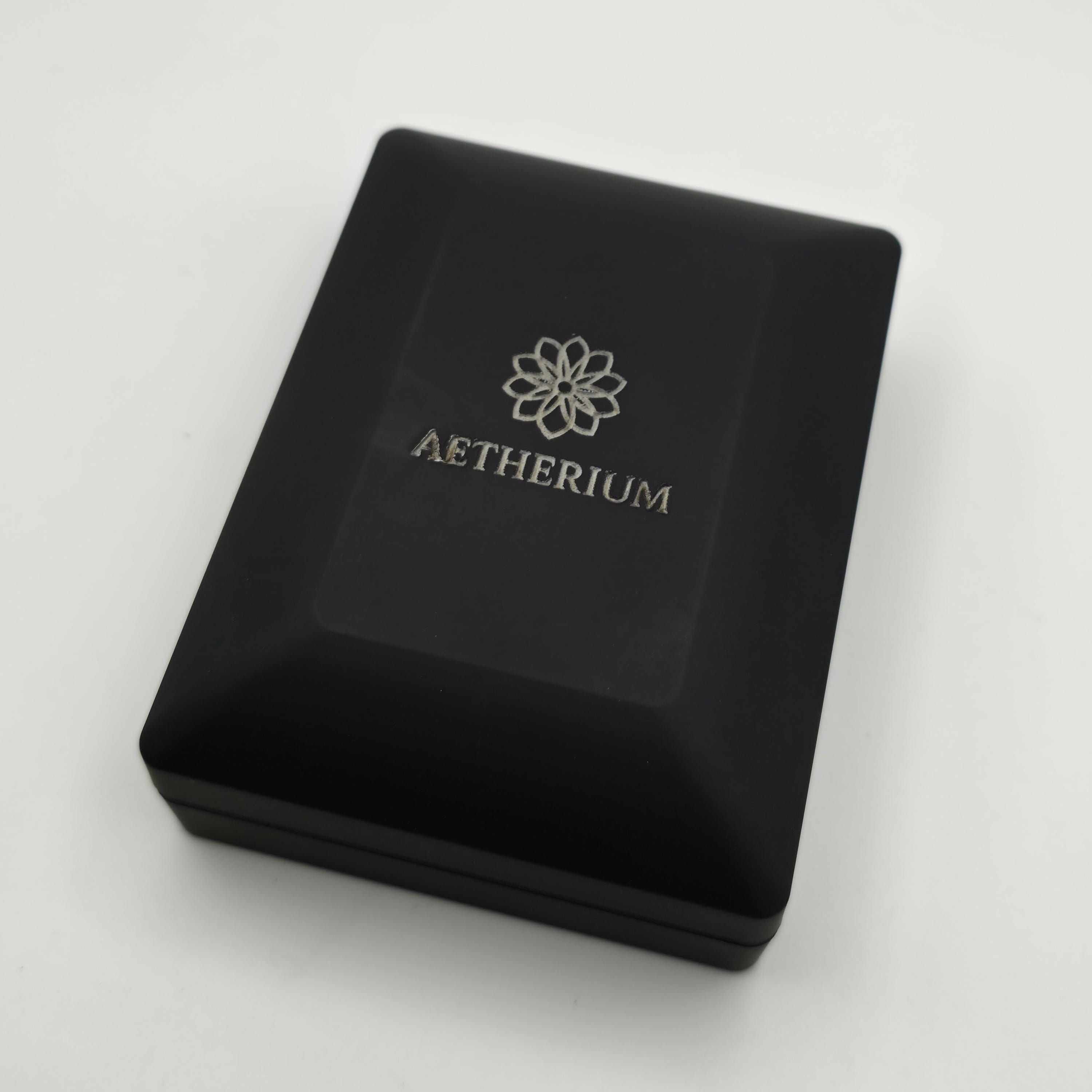 Closed black jewelry box featuring engraved silver Aetherium logo on the lid. Matte black finish provides elegant, modern presentation. Box doubles as protective case and luxury packaging, reinforcing the pendant’s premium gifting quality for anniversaries, weddings, and romantic milestones.