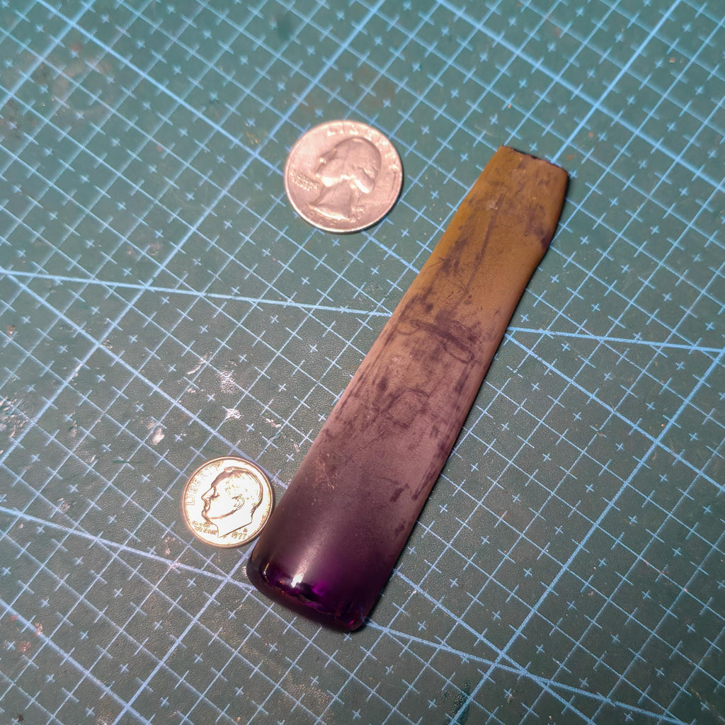 Large uncut Aetherium Alexandrite crystal next to a dime and quarter for scale, highlighting vivid purple transition and smooth boule surface. Ideal faceting rough for jewelers, lapidaries, and gemstone collectors seeking premium synthetic alexandrite stock.