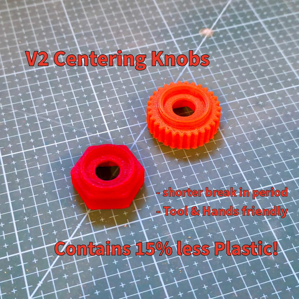 Two red centering knobs displayed on a cutting mat — one hexagonal, one with a fine-tooth grip pattern. Text notes shorter break-in period, ergonomic handling, and reduced plastic use. These updated components provide smoother centering for abrasive wheels with better tool contact and durability.