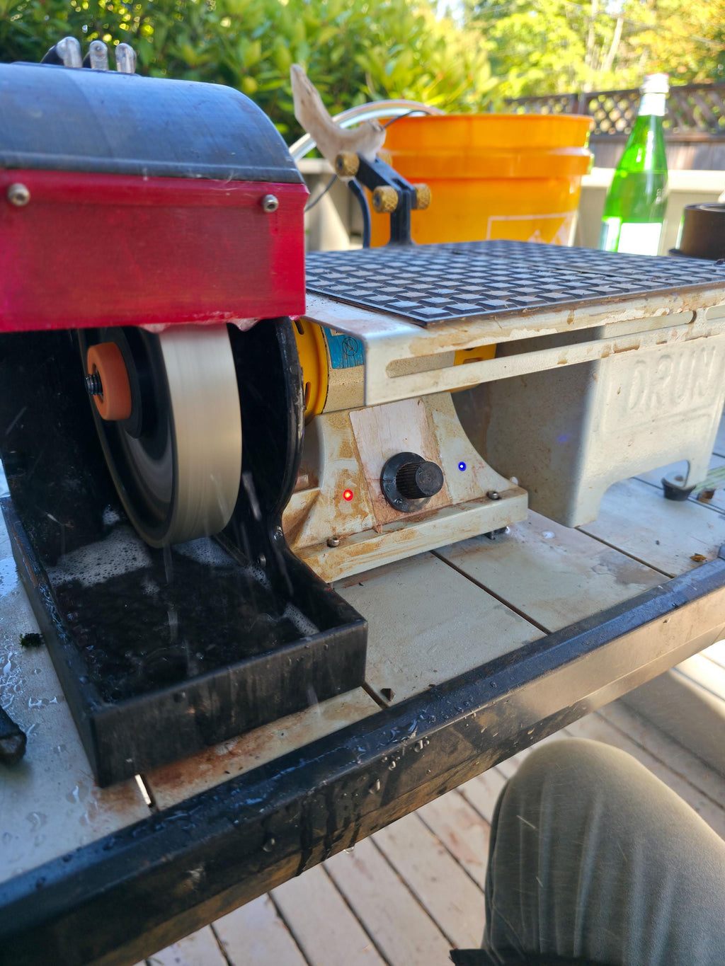 Image of the MakerSpace Edition machine running outdoors with water flow visible across the lapidary wheel and saw table. The setup demonstrates real-use conditions for wet grinding and trimming stone with a 110V bench lathe motor and reinforced housings built for durability and precision.