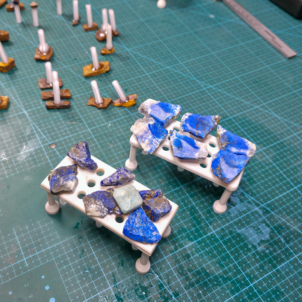 Multiple magnetic dop trays arranged in parallel, each holding rough and partially finished stones on dop sticks. The trays support batch processing and repeatable lapidary workflows by keeping stones upright and organized during grinding, shaping, and polishing stages.