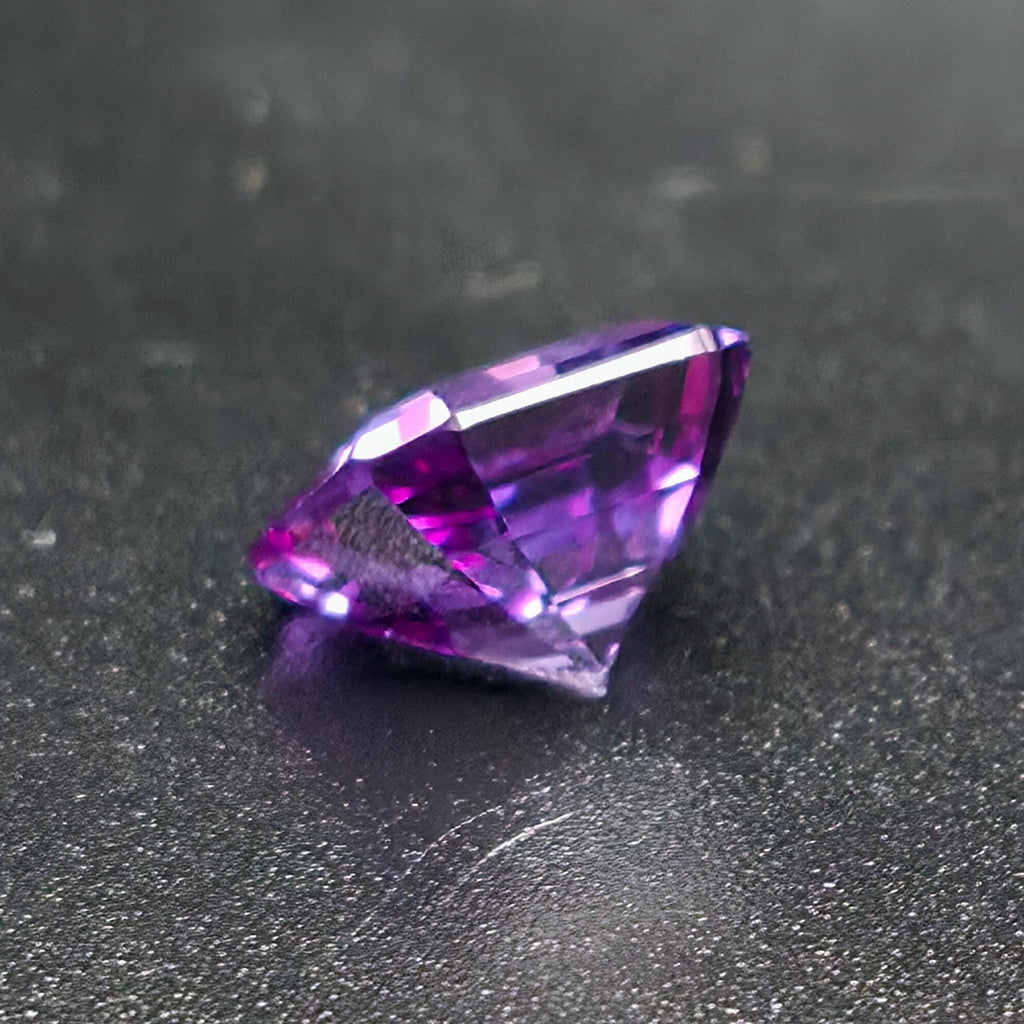Close-up of a polished purple faceted gemstone demonstrating optical clarity and precision cutting. Used to showcase results possible from custom lapidary tooling, CNC-machined fixtures, and prototype gem-processing workflows.