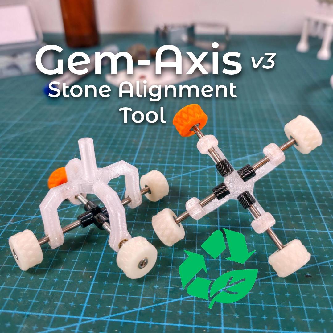 Two Gem Axis V3 stone alignment jigs on a green cutting mat in a bench setting. Clear recycled-polycarbonate bodies with stainless rods, white knurled wheels, and bright orange high-vis knobs. A green recycle-leaf icon appears at lower right. On-image text: “Gem-Axis v3 • Stone Alignment Tool.” Scene conveys precision centering at the dop to reduce epoxy drift and carat loss.