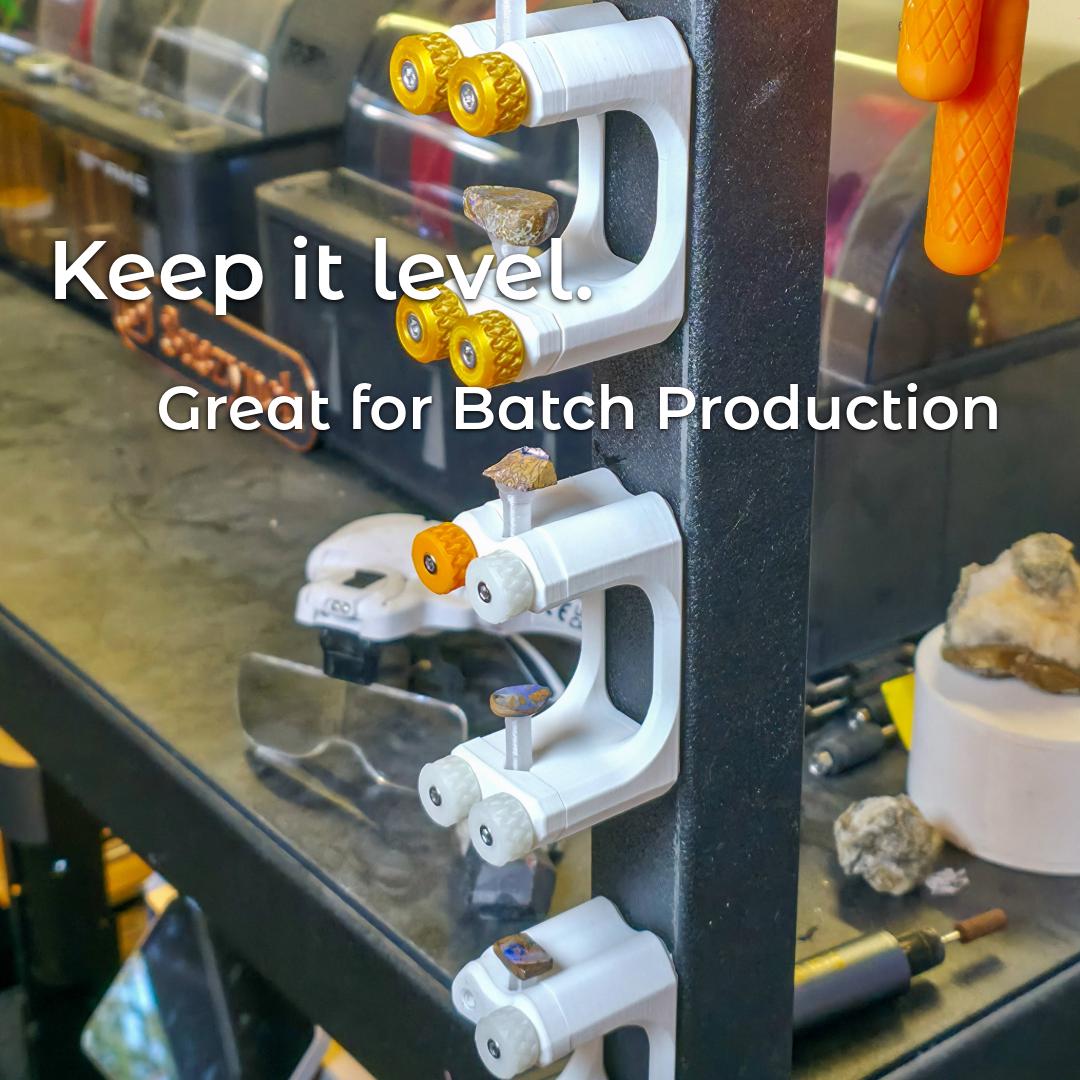 "Multiple Gem Xfer fixtures holding dop sticks with stones in various stages of cutting, mounted vertically on a metal workbench leg. The text overlay reads 'Keep it level. Great for Batch Production.' The image highlights alignment consistency and efficiency for gem cutting production runs."