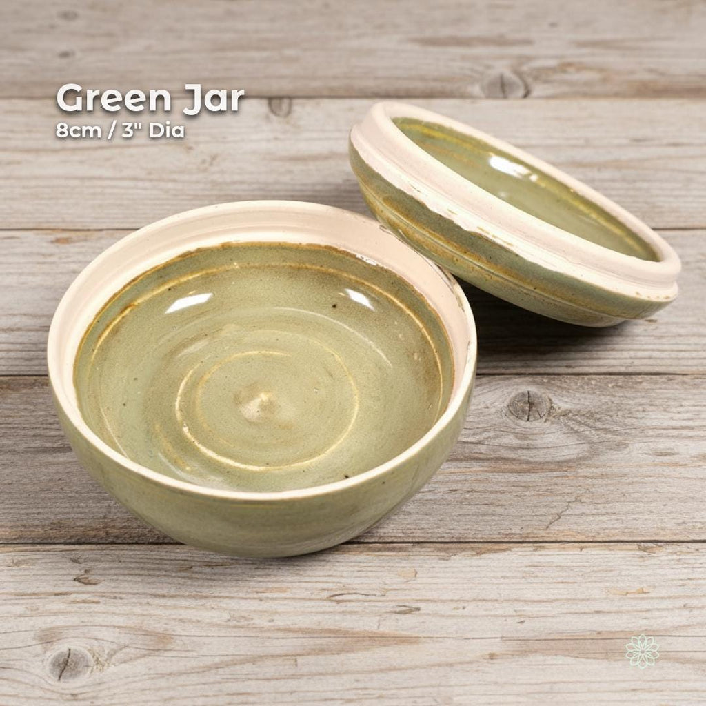Green glazed ceramic altar jar with the lid resting behind the bowl to show the interior