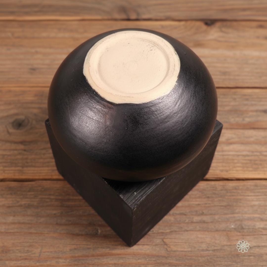 A close front view of the Rusty Bowl altar vessel on warm farmhouse wood. The exterior features layered smokey red, brown, and black glazes with a rounded, hand-thrown silhouette. No text overlays appear in this image. Part of the altar jar set offering.