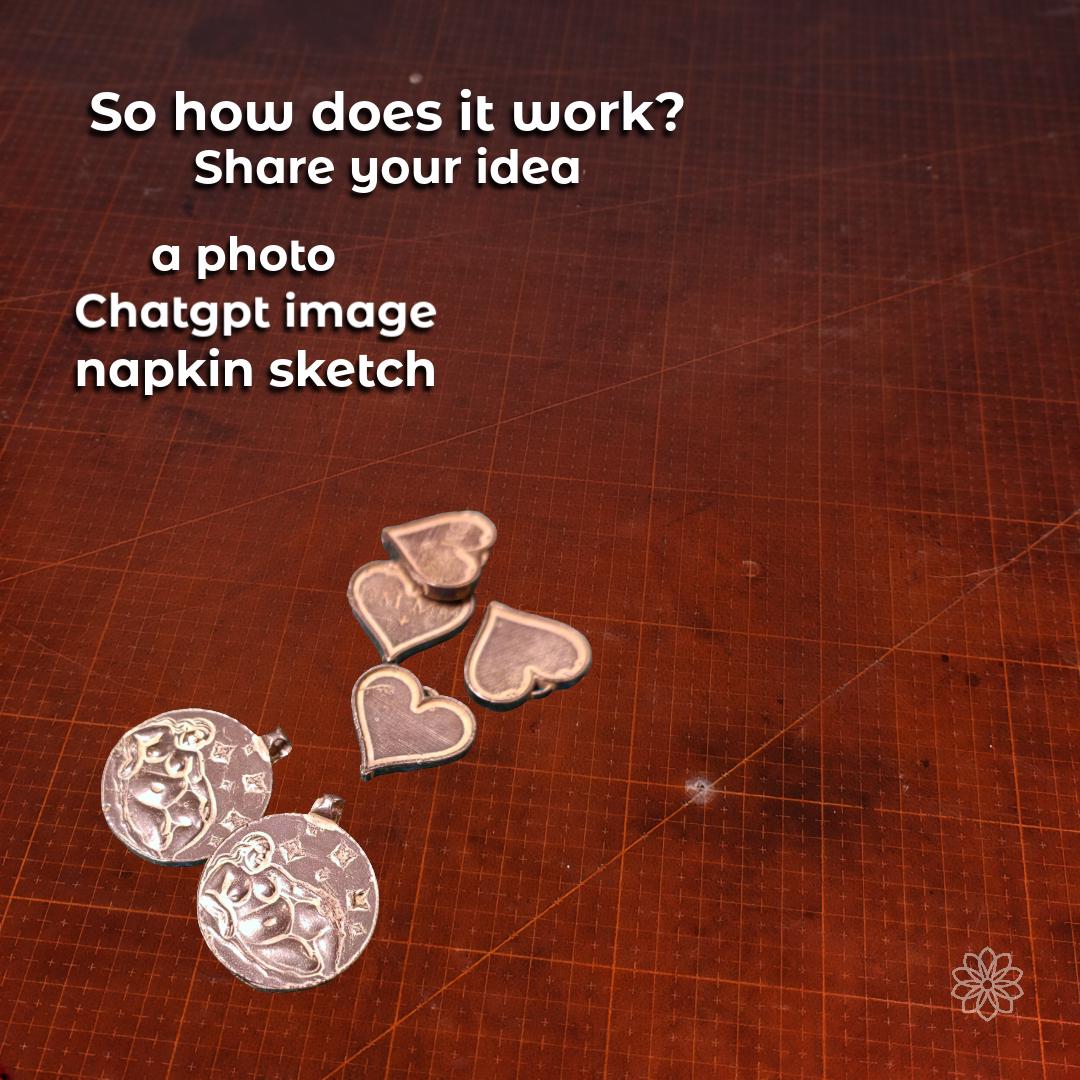 Custom pendants and heart blanks laid out on a worn drafting board, illustrating how clients start the design process by sharing photos, AI-generated images, or sketches. Shows early-stage metal blanks ready for shaping. Communicates an approachable, collaborative custom jewelry workflow.