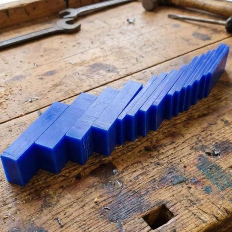 Long row of blue carving wax blanks lined up by thickness on a workbench. Durable jeweler’s wax for carving ring shanks, sculpting custom bezels, or roughing out CNC-milled jewelry masters prior to investment casting.
