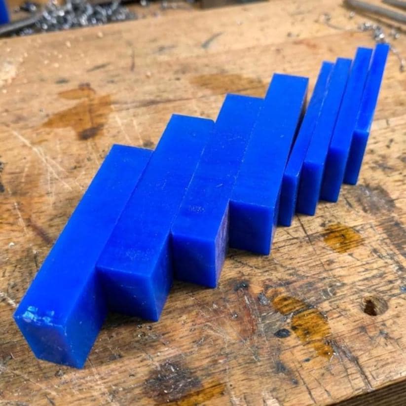 Blue jeweler’s carving wax blocks arranged in a stepped row on a workbench. Solid, opaque wax used for ring carving, pendant shaping, and CNC wax pattern machining. Ideal for detailed lost-wax casting models and hand-tooled jewelry prototypes.