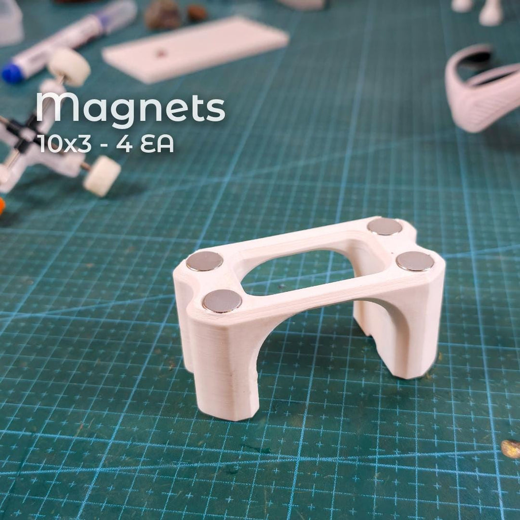 Bottom view of the Gem-Xfer epoxy cure station showing four recessed neodymium magnets installed into the 3D print. Magnets add bench stability and metal-surface adhesion. Scene highlights assembly steps for makers printing the digital jig and preparing it for gemstone transfer, epoxy curing, and dop alignment in faceting workflows.