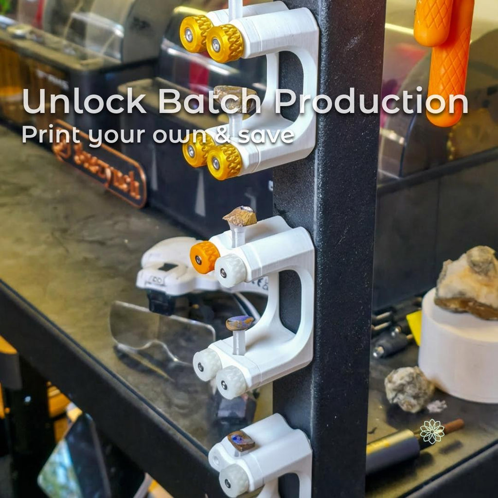 “Gem-Xfer epoxy cure station and transfer jig mounted vertically on a steel tool rack, each printed in white bioplastic with orange and white knurled knobs holding gemstone dops in place. Multiple units are stacked in a column to show batch production workflow for lapidary makers. Workshop benches, tools, and stones appear softly blurred in the background.”