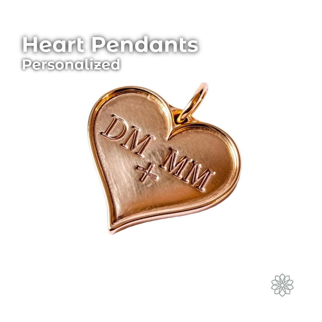 A polished engraved heart pendant milled from solid brass with two sets of initials on the front, shown against a clean white background. The heart features a smooth reflective surface, a top loop for adding a chain, and crisp engraved lettering, highlighting its personalized and sentimental jewelry style.