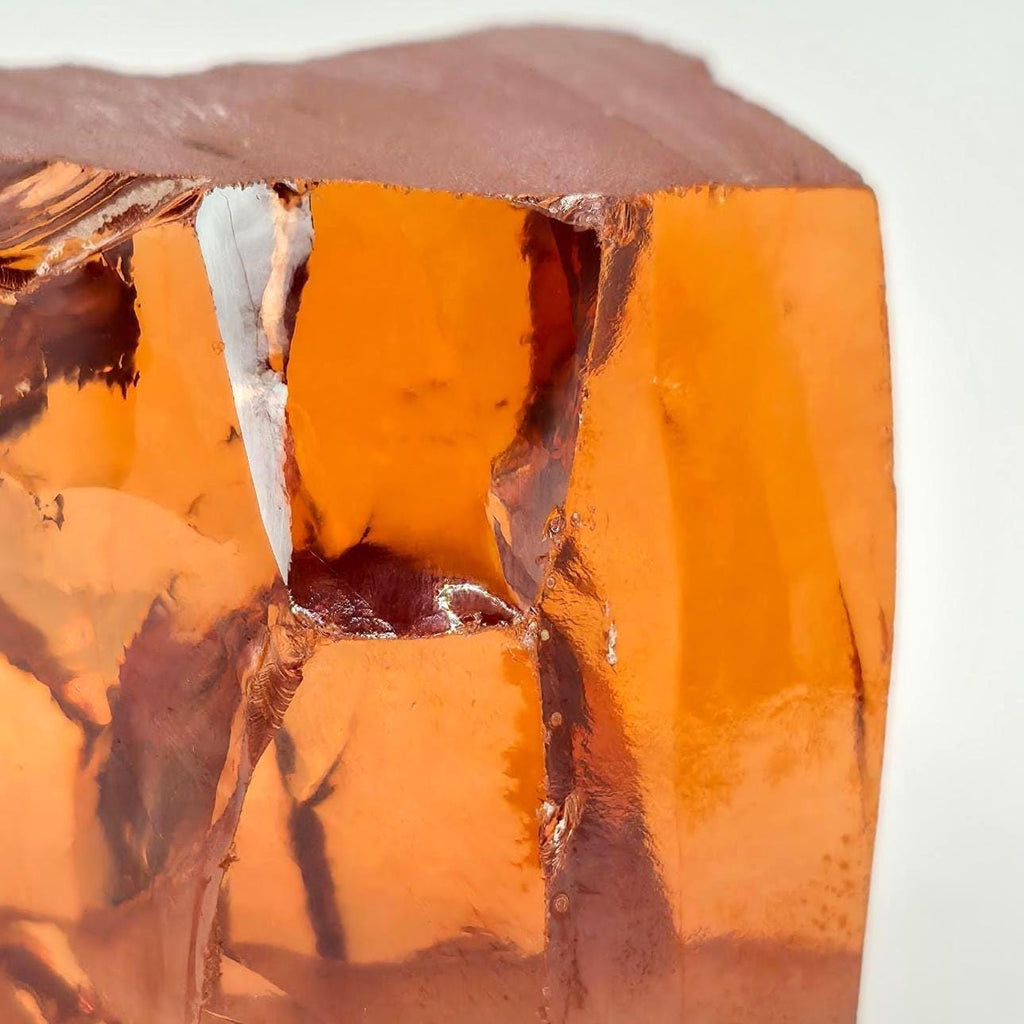 “Macro detail of champagne zirconia rough with orange-gold transparency and sharp edges. High clarity rough material used by gem cutters for precision faceting and training cuts.”