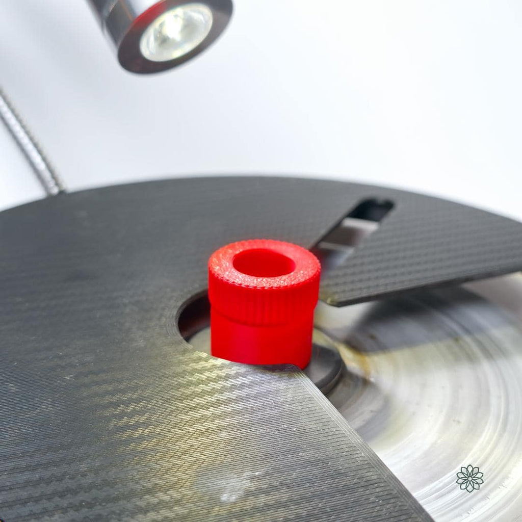 “Red knurled quick-change lap nut installed on the main spindle of a Vevor faceting machine. The carbon-fiber top plate frames the threaded insert, showing how the upgraded thumb screw replaces the factory nut for rapid lap changes. Ideal for switching between diamond, topper, and polishing laps without interrupting workflow.”