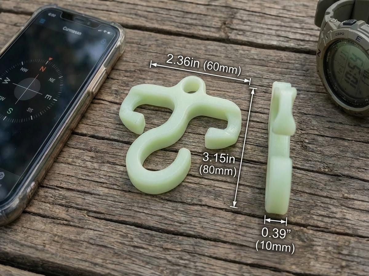 Close-up of a mini paracord hook on a wooden surface beside a compass app and digital watch. Measurements show 2.36 inches wide, 3.15 inches tall, and 0.39 inches thick. The glow bioplastic design emphasizes compact, ultralight camping use.