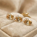 “Three oval-cut champagne cubic zirconia gemstones displayed on a soft beige jewelry tray, with a gold ring in the background. The stones show bright faceting, warm golden sparkle, and calibrated 9×7 mm proportions, ideal for custom rings, pendants, and fine jewelry design.”