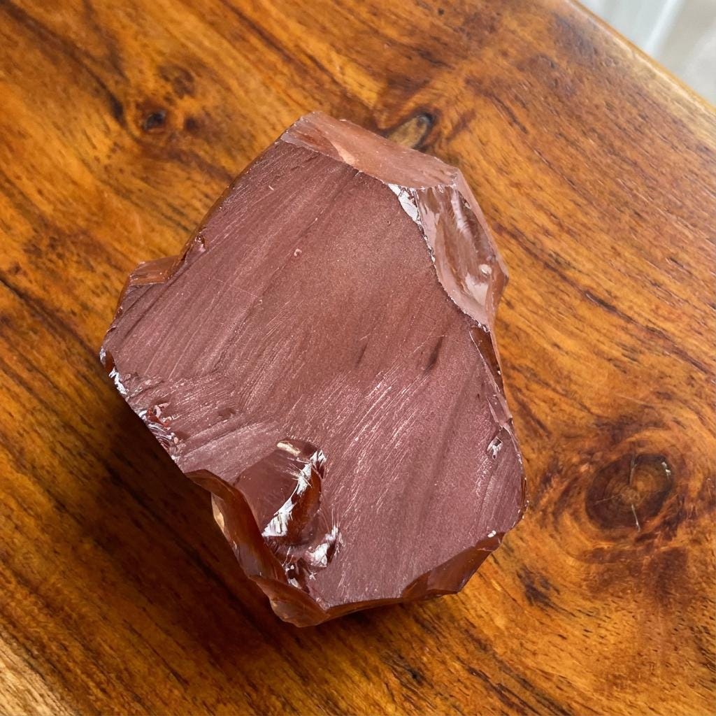 “Champagne CZ rough block photographed on a wooden surface, showing satin-textured cleavage faces and transparent golden interior. Large piece suitable for lapidary slicing and gemstone cutting.”