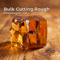 “Large block of champagne-colored cubic zirconia cutting rough on a wooden table, showing glassy fracture faces and deep amber internal color. Used for gemstone faceting practice, jewelry prototyping, and lapidary work.”