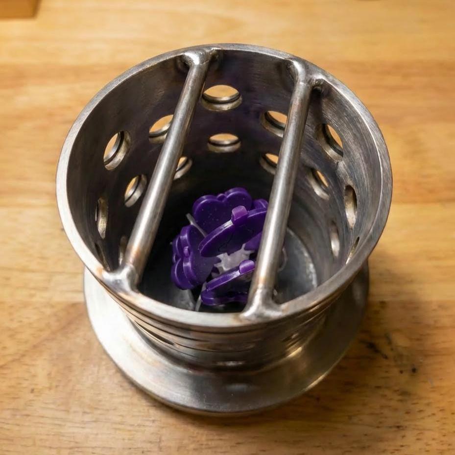 “Stainless steel casting flask containing a purple wax sprue tree ready for investment casting. Demonstrates the shop’s ability to create prototype cast parts for jewelry, mechanical components, and custom metalwork.”
