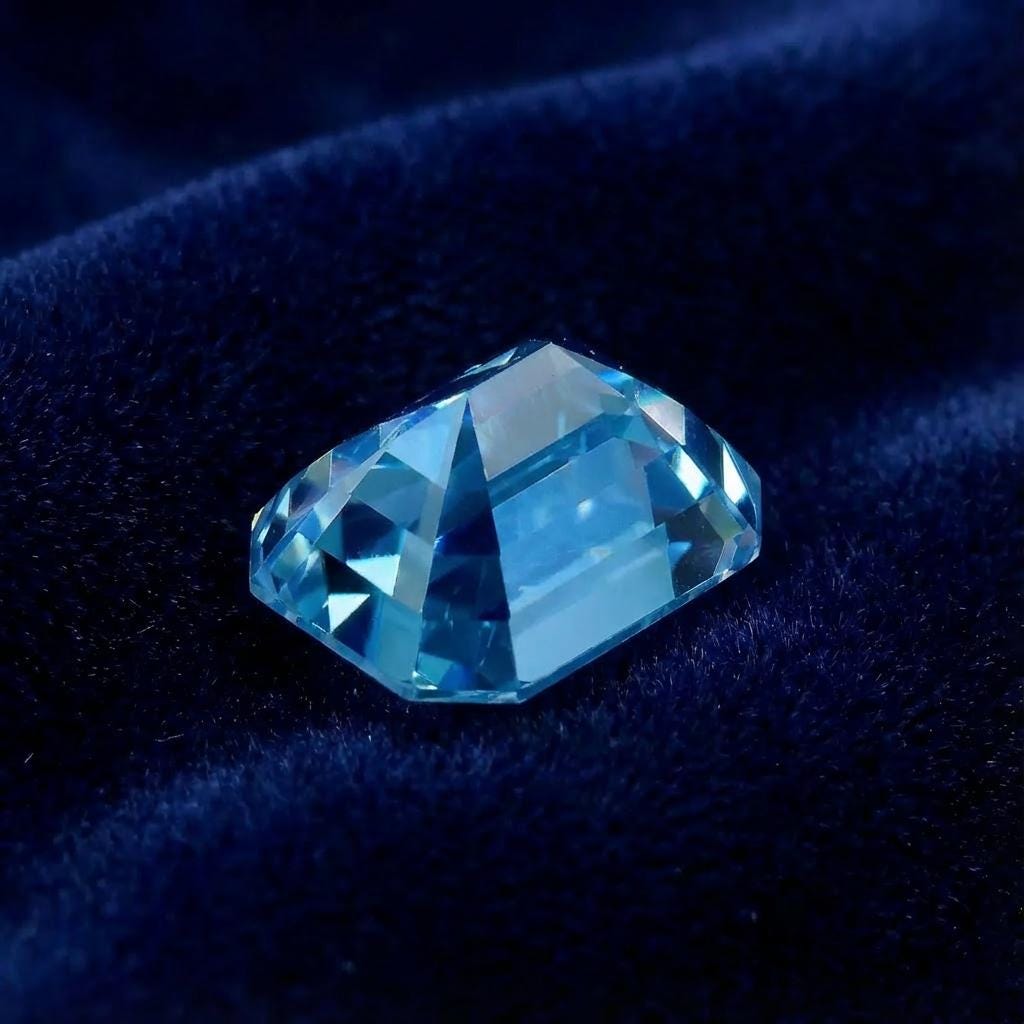 Side-angle view of a lab-grown blue moissanite showing pavilion depth and step-cut structure. Facet junctions appear crisp, with even spacing and consistent polish. The emerald cut reveals controlled light behavior through long reflective planes rather than sparkle scatter, ideal for designers prioritizing clarity and architectural form.