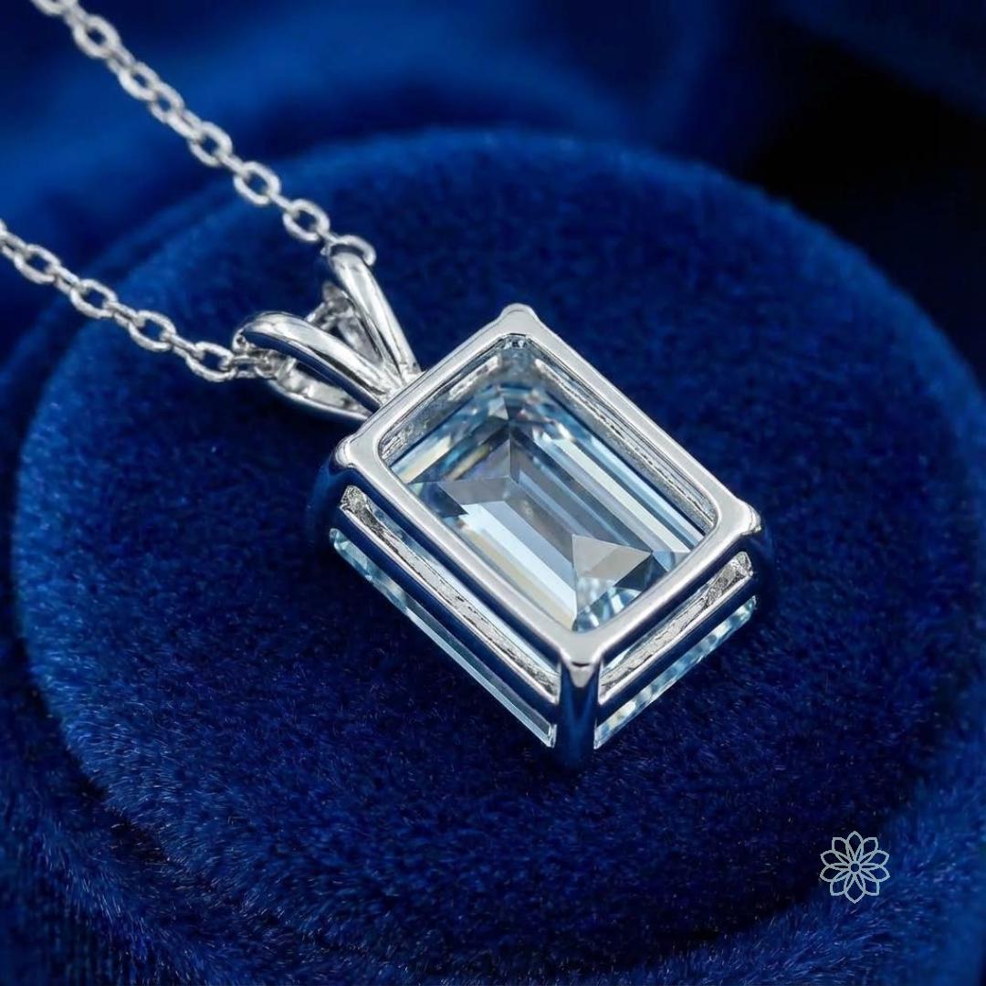 Emerald-cut blue moissanite displayed in a geometric bezel-style pendant. The clean metal lines echo the stone’s rectangular form, emphasizing symmetry and precision. This image demonstrates compatibility with modern, architectural jewelry designs and reinforces the stone’s suitability for intentional, custom fabrication.