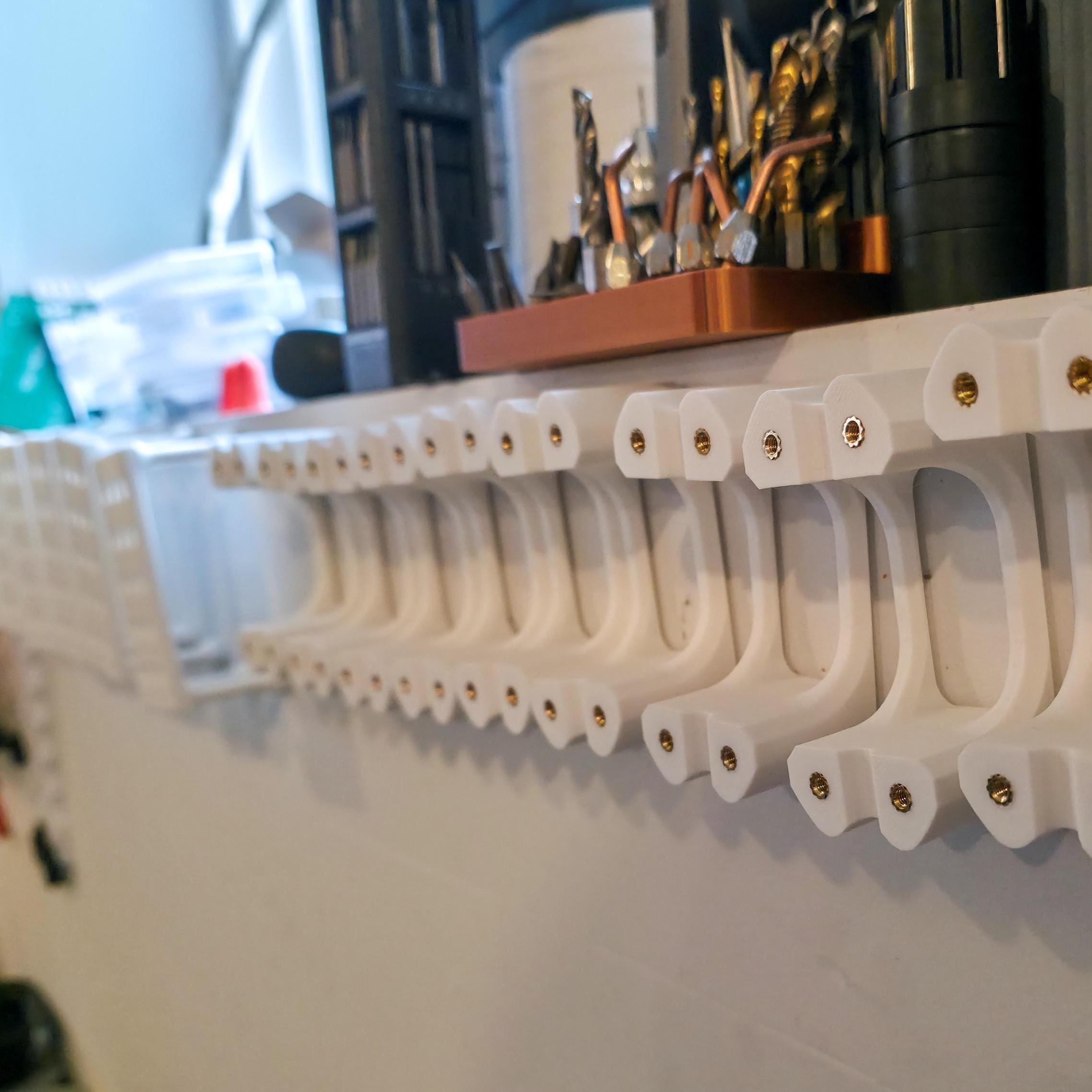 Dozens of finished Gem-Xfer epoxy cure stations lined up on a workshop shelf. Heat-set inserts are installed in each tower. The image reinforces final assembly quality and shows how the digital file can be used to produce consistent, professional-grade transfer jigs for lapidary work.