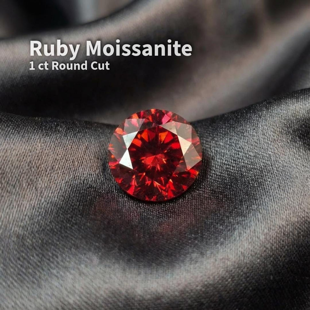 1 carat ruby red moissanite gemstone in a round Russian brilliant cut, photographed loose on dark fabric. The stone shows deep crimson color, sharp facet symmetry, and high internal fire typical of precision fancy brilliant cuts. Loose gemstone suitable for custom jewelry, engagement rings, or fine pendant designs.