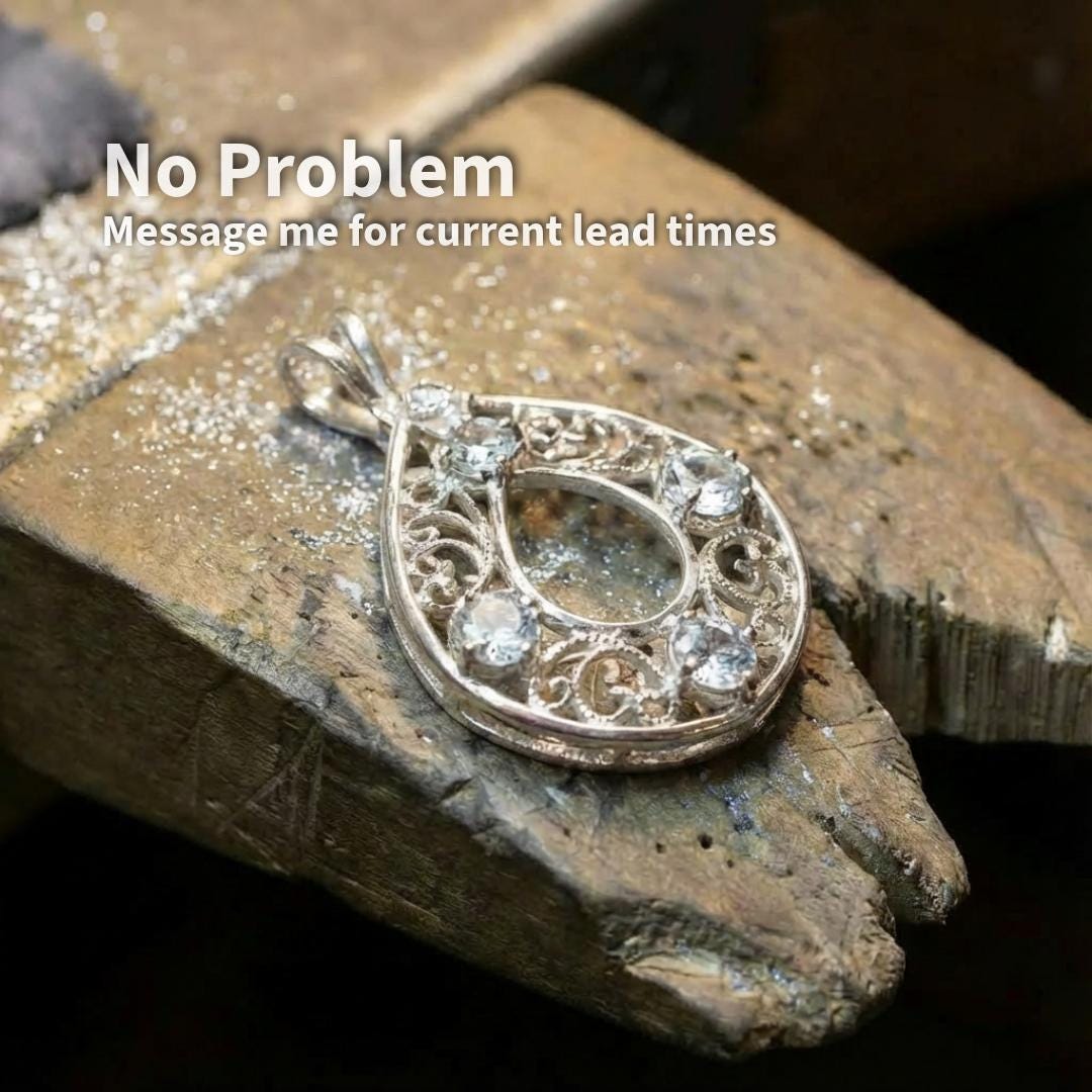 White sapphire accent stones set into a silver pendant during bench work, 2 mm round cut sapphires used for pavé and decorative detailing, shown on jeweler’s work surface.