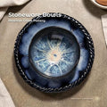 Overhead view of a small reactive glaze stoneware bowl nested inside a larger braided-rim stoneware bowl on a wood plank table. Both bowls have blue crystalline glaze patterns. White text in the top left reads “Stoneware Bowls” and “Reactive Glaze Pottery.” A small Aetherium x Archibald logo appears in the bottom right corner.