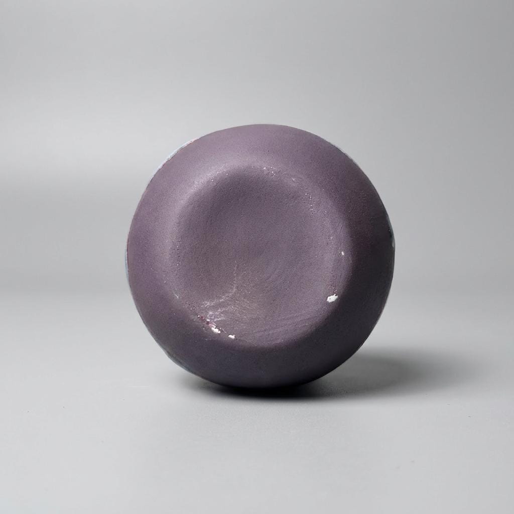 Bottom view of a handmade ceramic art vase showing the smooth, unglazed clay base. The circular foot is evenly formed, with subtle firing marks and natural variations in the clay surface. This image emphasizes craftsmanship, stability, and the tactile quality of the ceramic material.