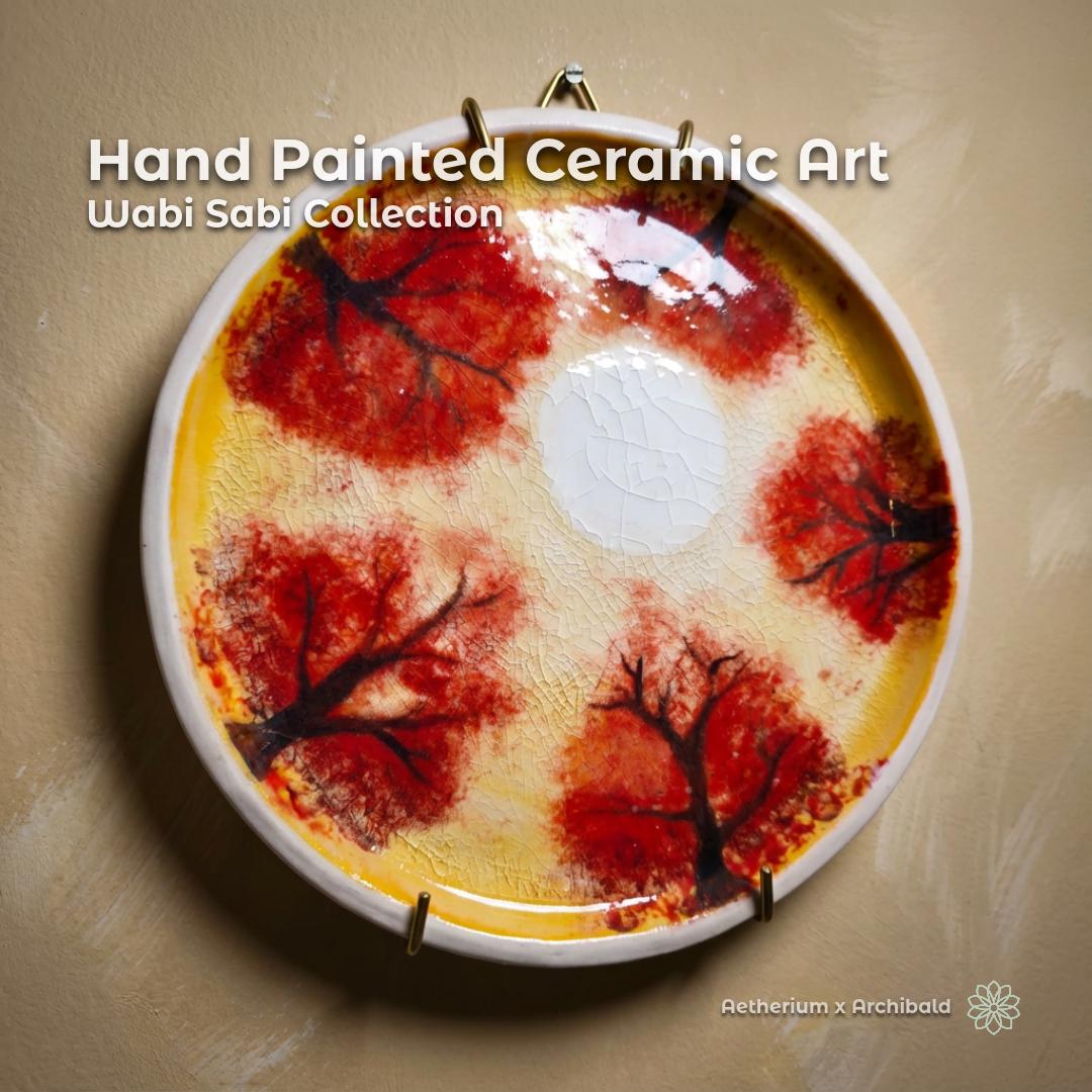 Hand-painted ceramic wall plate from the Wabi Sabi Collection, featuring red autumn tree forms around a pale center with visible kannyū crackle glaze. Shown mounted on a textured plaster wall above a wooden shelf, emphasizing organic Japanese-inspired pottery aesthetics.