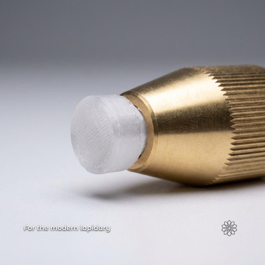 Text reads “For the modern lapidary.” Close-up macro image of a brass faceting quiill holding a translucent polycarbonate dop tip. The printed surface texture is visible, highlighting a hybrid workflow that combines traditional brass tooling with 3D printed polycarbonate components for epoxy dopping and precision gemstone cutting.
