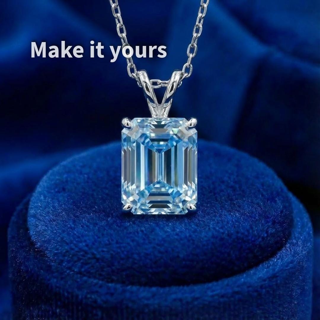 Emerald-cut blue moissanite shown set in a silver pendant with a clean, minimal bail. The step-cut facets align with the vertical orientation of the setting, demonstrating how the stone translates into finished jewelry. Image represents a design example only, highlighting customization potential rather than a finished product.