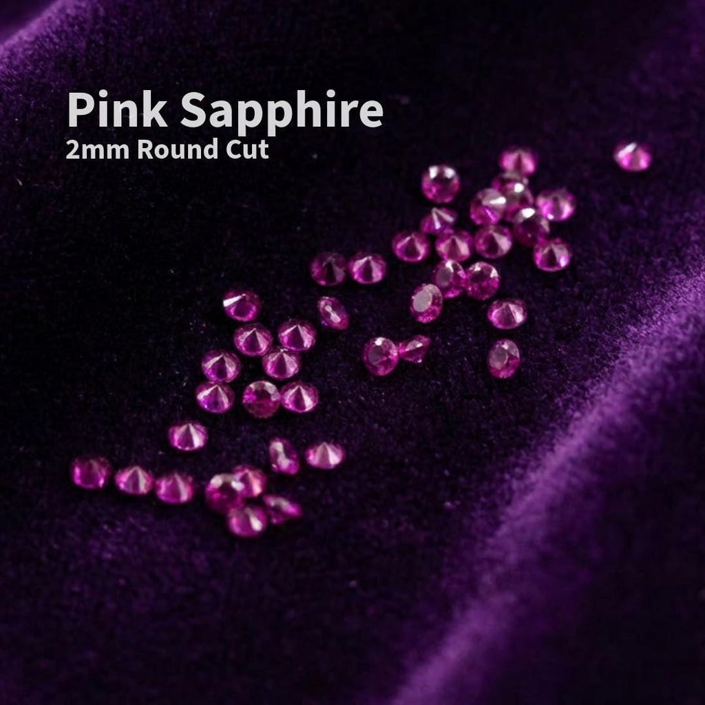 Lab grown pink sapphire accent stones, 2 mm round cut, scattered on deep purple velvet. Small precision-cut sapphires used as jewelry embellishment stones for rings, bands, and fine detail settings. Bright magenta pink color with clean facets shown loose for scale and clarity.