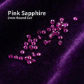 Lab grown pink sapphire accent stones, 2 mm round cut, scattered on deep purple velvet. Small precision-cut sapphires used as jewelry embellishment stones for rings, bands, and fine detail settings. Bright magenta pink color with clean facets shown loose for scale and clarity.