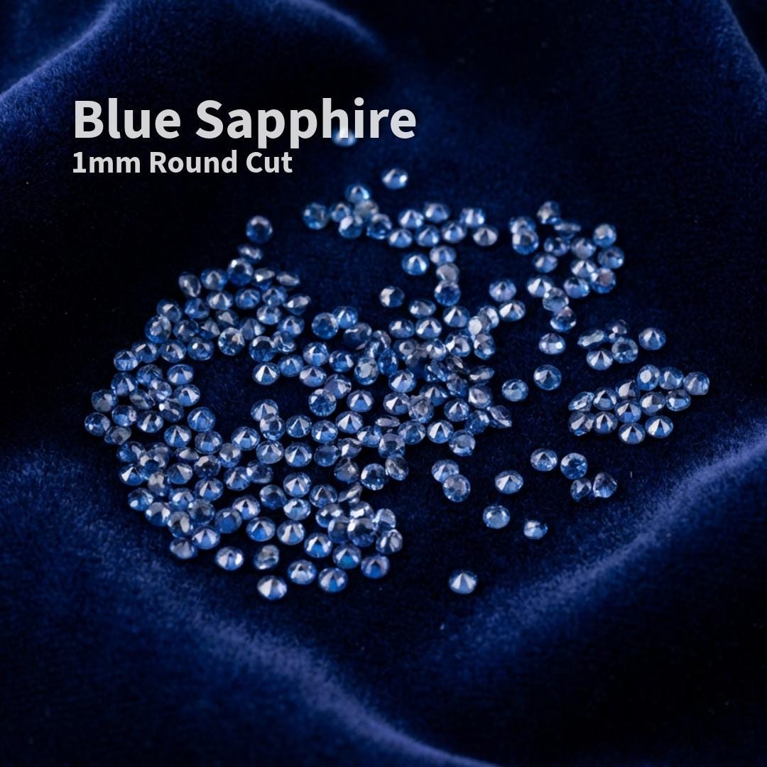 Lab-grown blue sapphire accent stones, 1 mm round brilliant cut, displayed on deep blue velvet fabric. Small precision-faceted sapphires shown as loose jewelry supply stones intended for pavé, micro-setting, and fine detail jewelry work.