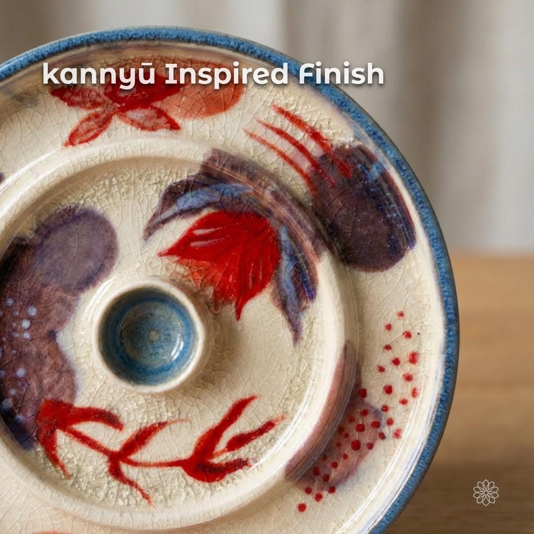 Close-up of the ceramic incense dish surface highlighting the intentional crackle glaze (kannyū-inspired finish). Fine crack lines spread across a creamy glaze base with hand-painted abstract botanical forms in red and muted purple tones. The raised central incense holder and blue-glazed rim are visible, emphasizing texture, depth, and handmade variation.