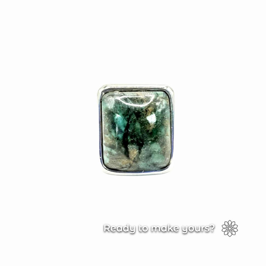 Macro photo of a finished square cabochon ring with a polished green-blue stone in silver bezel. Clean lines and mirror finish emphasize craftsmanship possible from PolyCast digital ring blank designs.