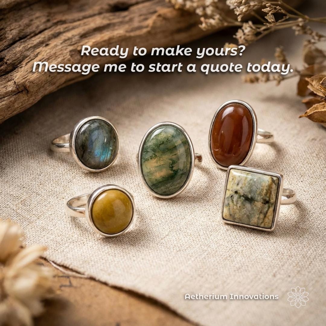 Five finished cabochon rings set in polished silver, each featuring a different natural stone, arranged on a textured fabric surface with dried botanical elements. The rings vary in shape and stone color, illustrating the final outcome possible after casting, finishing, and setting, without implying mass production.