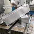 A long 200 mm bar of 6160-T6 aluminum resting on a CNC mill table, showing clean brushed faces, sharp edges, and machining coolant spots around it. Ideal for precision milling, prototyping, fixturing blocks, and custom CNC parts.