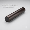 Black Delrin acetal rod shown on a clean white background, labeled CNC and lathe stock. Solid round engineering plastic rod with smooth surface finish, used for machining bushings, spacers, fixtures, and low-friction mechanical parts on CNC mills or lathes.