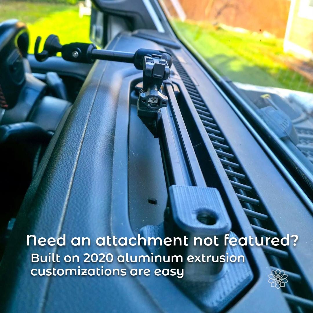 Close-up view of the dash accessory rail mounted in the Jeep dashboard recess, highlighting the aluminum 2020 extrusion and custom 3D printed mounting base. The image shows the low-profile fit against the dash surface and the adjustable arm connection point used for accessory mounting.