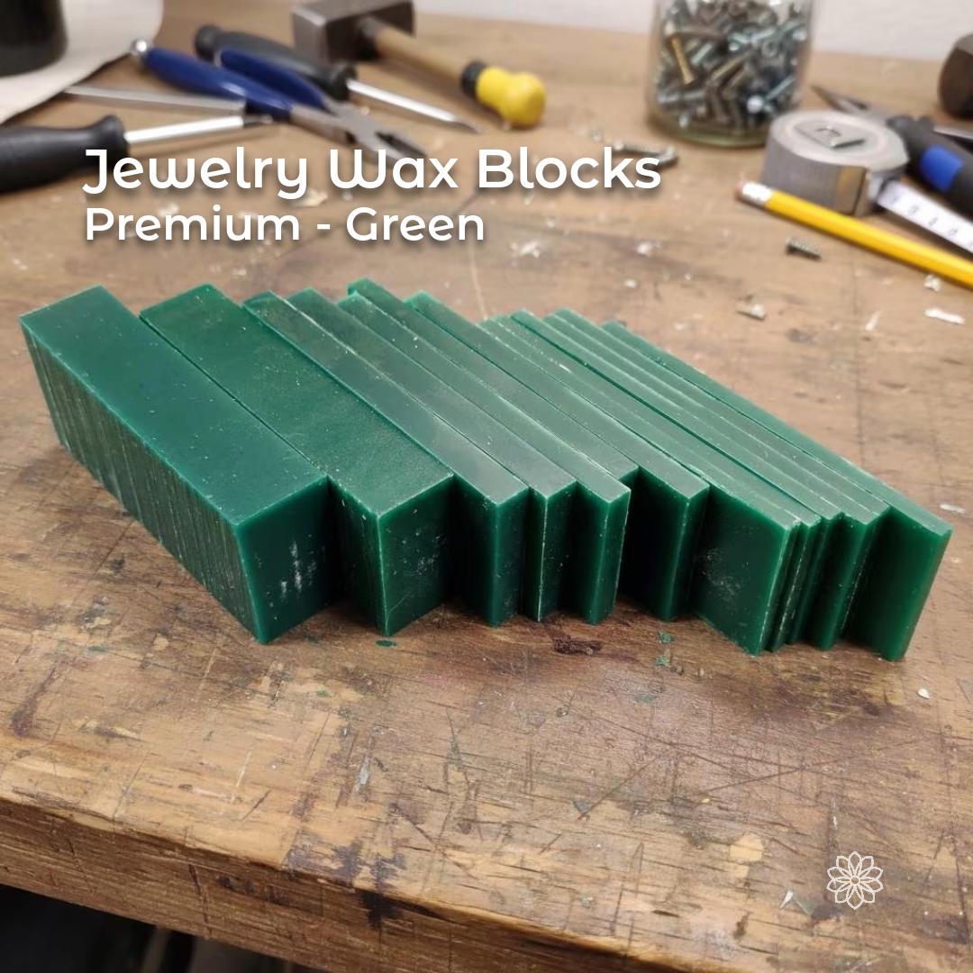 “A stack of rectangular green carving-wax blanks lined up on a workbench. The consistent thickness and smooth faces indicate machinable wax prepared for jewelry carving, CNC milling, or lost-wax casting patterns. Various tools and screws surround the stack in a workshop setting.”