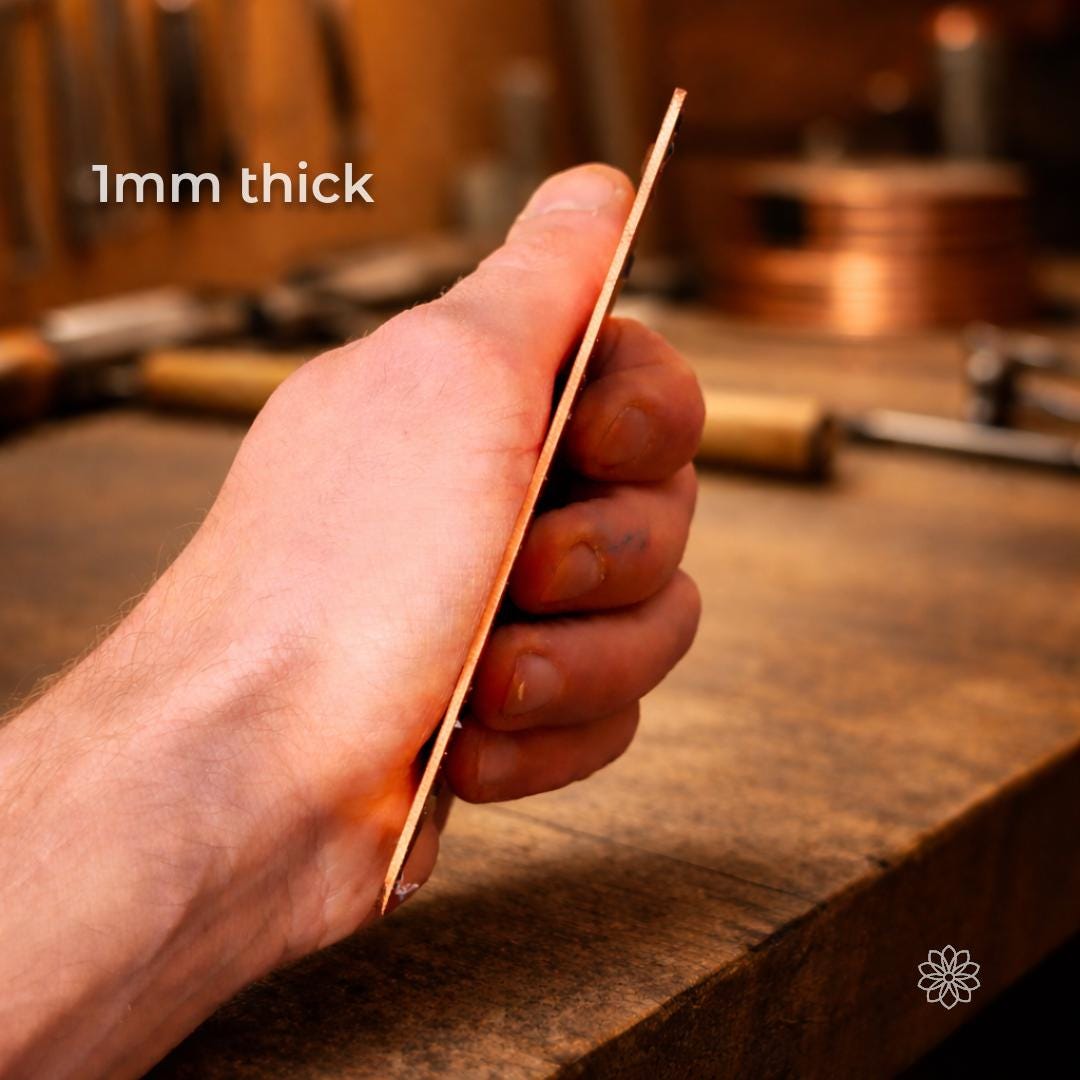 Side profile of a thin copper sheet held between fingers, showing a 1 mm thick copper plate with sharp, clean edges. The image highlights material thickness and rigidity, demonstrating suitability for CNC machining, electrical grounding plates, EMI and RF shielding, and precision metal fabrication work.