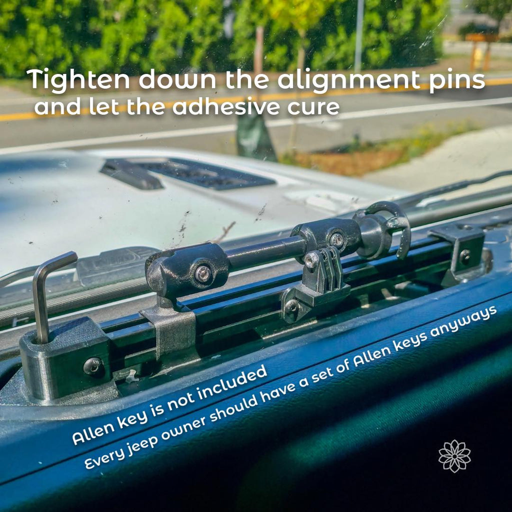 Dash-mounted accessory rail installed on the Jeep dashboard with alignment pins tightened into place. An Allen key is visible engaging the hardware, demonstrating final alignment and securing of the rail before allowing the adhesive to cure fully.