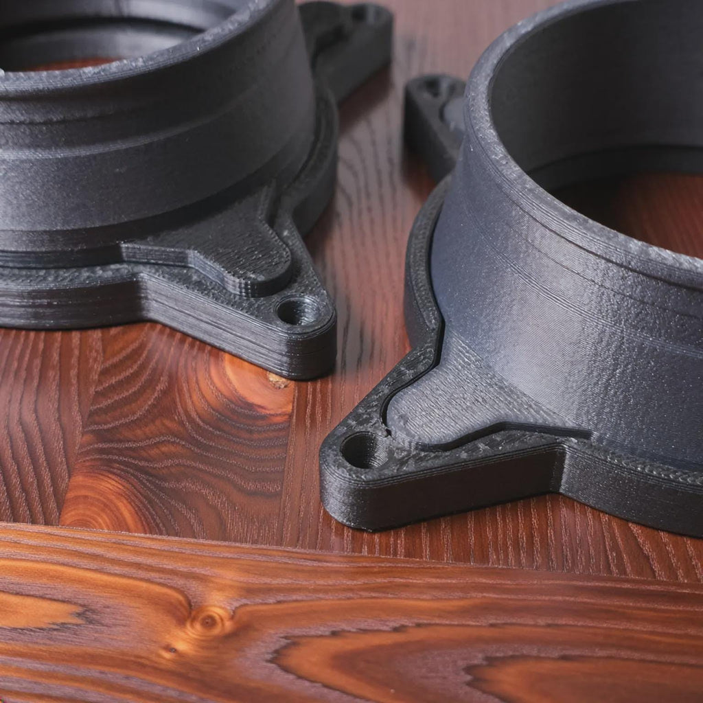 Close-up view of Vent Link through-hull adapter components resting on a wood surface, highlighting precision 3D-printed carbon fiber reinforced polycarbonate construction, clean layer lines, reinforced mounting tabs, and consistent wall thickness. This image emphasizes build quality, durability, and dimensional accuracy for diesel heater airflow systems.